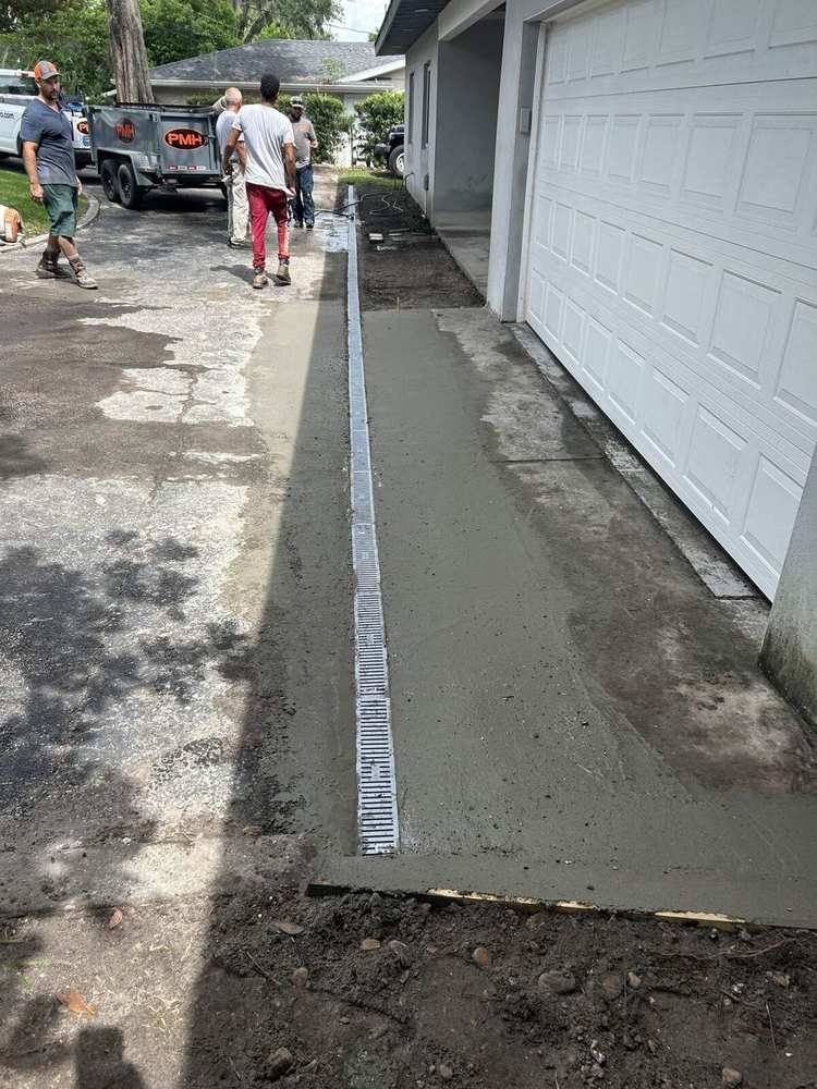 Linear channel drain set into a concrete driveway beside a garage