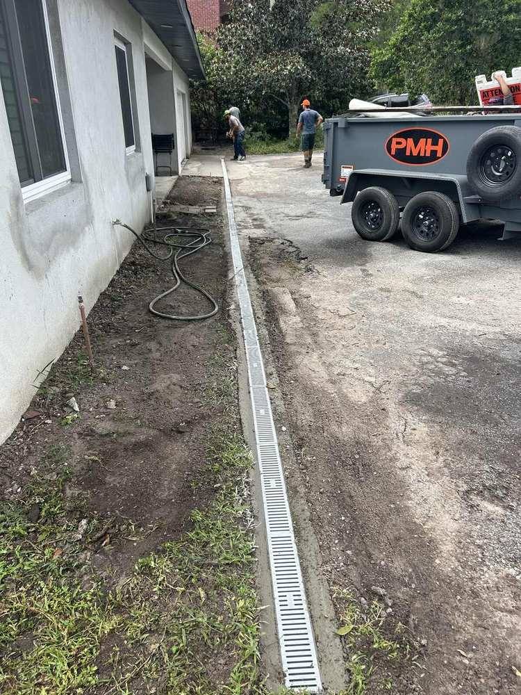 Long grated channel drain set into concrete beside a driveway